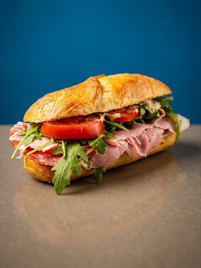 Panino Classico with layers of cured meats, tomato and wild rocket on a crusty roll