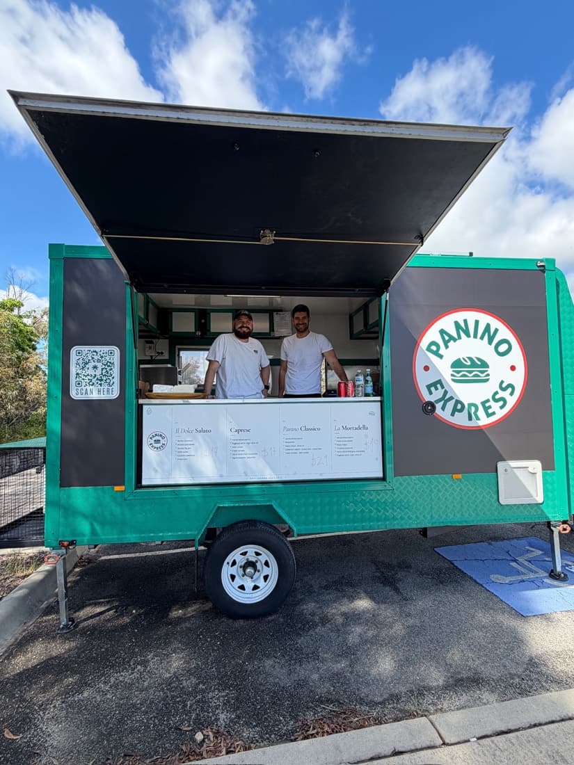 The Panino Express trailer parked at a market with its awning raised, the menu board along the front of the hatch